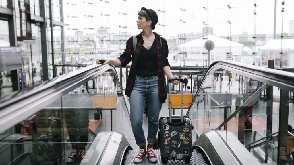 woman with luggage waiting to reach top of escalator at airport