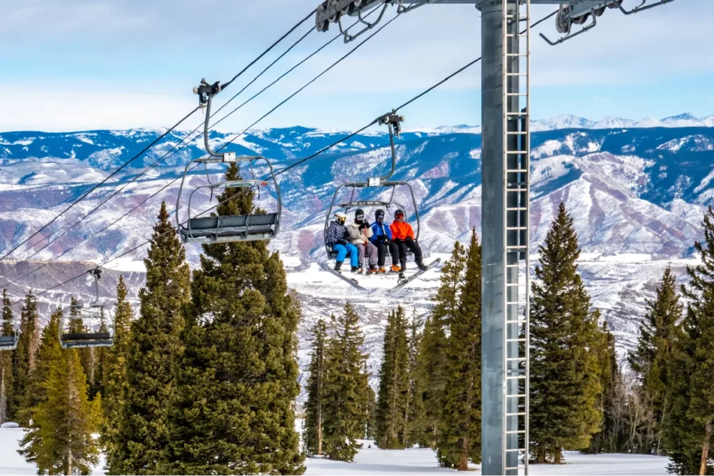 Friends on ski trip riding ski lift to slop starts on trip planned with acx travel.