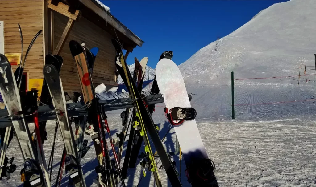 Skis and snowboards in rack awaiting use.