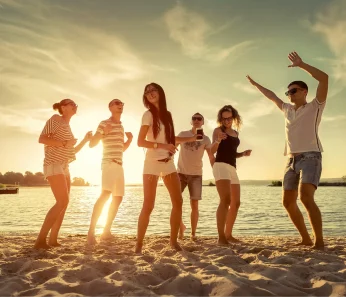 Friends dancing on island beach booked with acx travel.