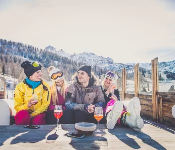 Friends taking a break from skiing and visiting the ski lodge for some drinks on an excursion booked with acx Travel.
