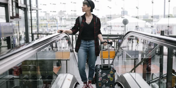 woman with luggage waiting to reach top of escalator at airport